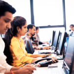 Outsourcing, Mumbai, Service - Group of call center executives seated in a row working on their desktop PC